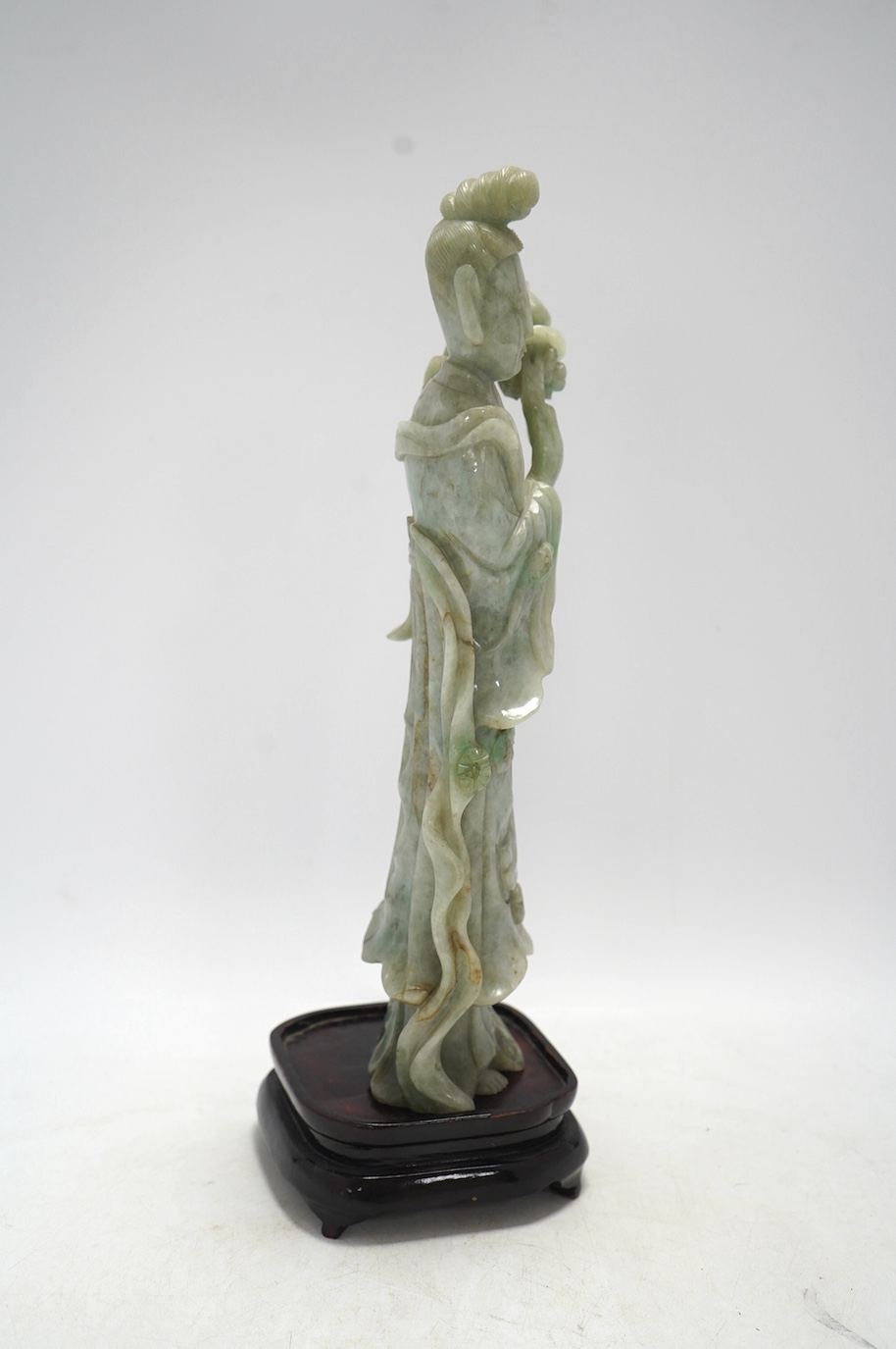 A Chinese jadeite carving of Guanyin, on associated hardwood stand, 38cm high. Condition - fair